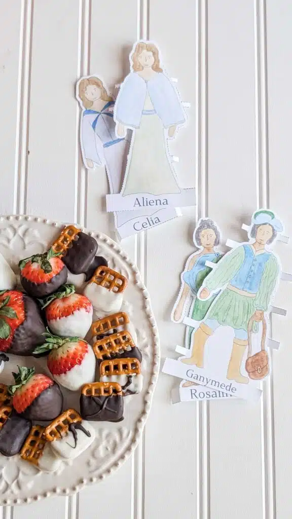 Chocolate Covered Strawberries 1 1 - Read-Aloud Revival ® with Sarah Mackenzie Plate of chocolate-dipped strawberries and waffle cookies beside handmade paper dolls with names on a light wall.