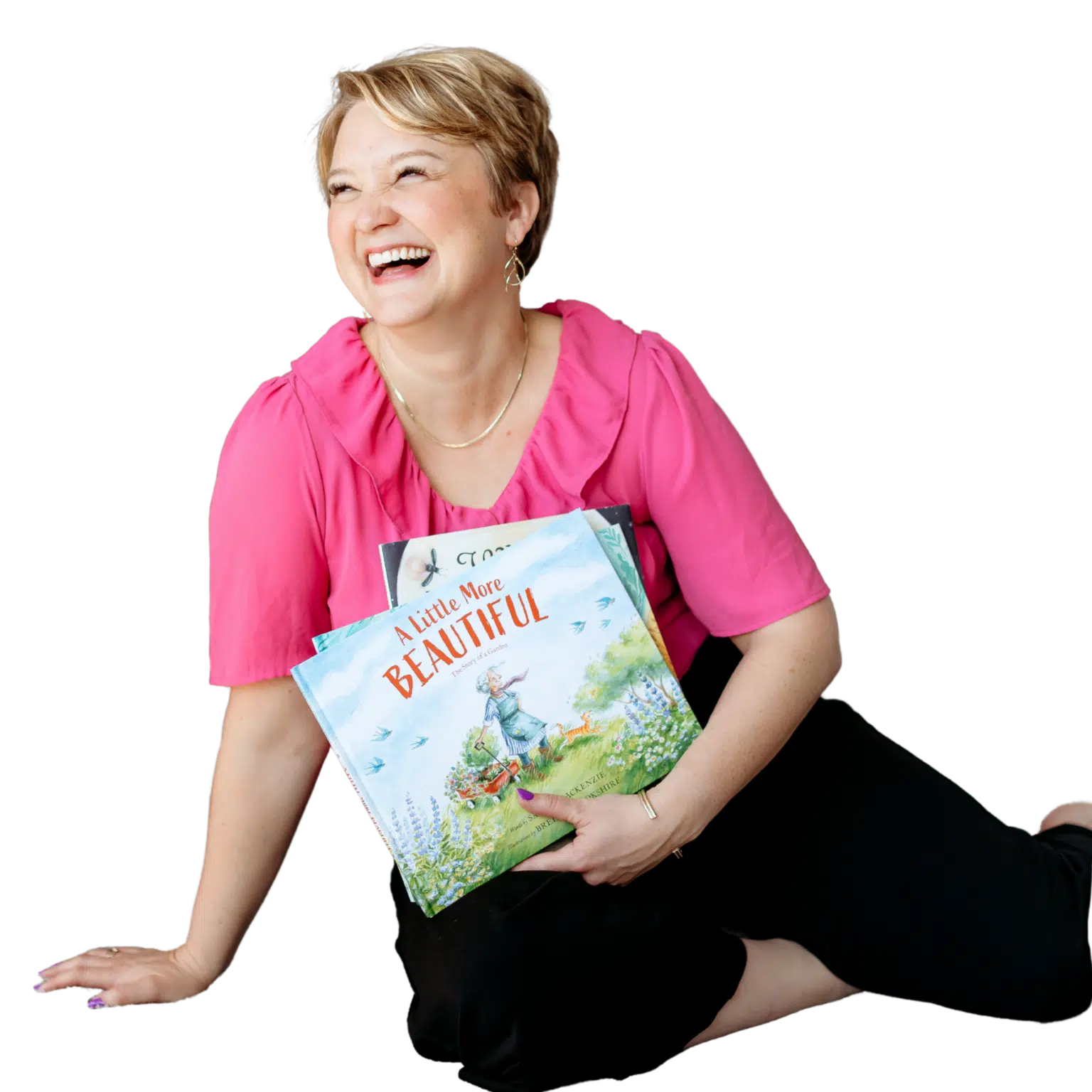 Sarah homepage cropped - Read-Aloud Revival ® with Sarah Mackenzie Smiling woman with short blond hair in a pink blouse, holding colorful books against a black background.