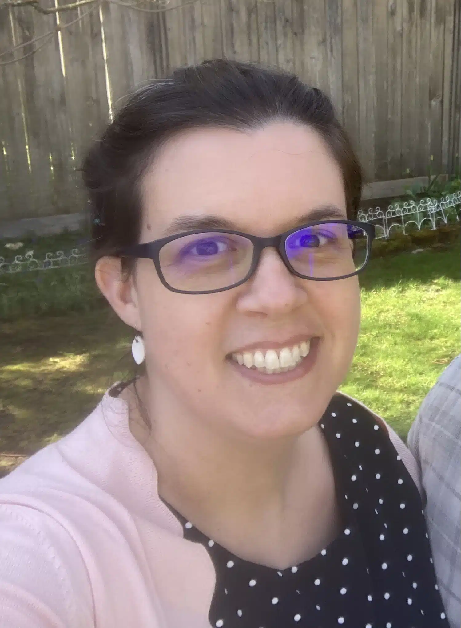 Tavia White - Read-Aloud Revival ® with Sarah Mackenzie Smiling woman wearing glasses outdoors with a wooden fence and greenery in the background.