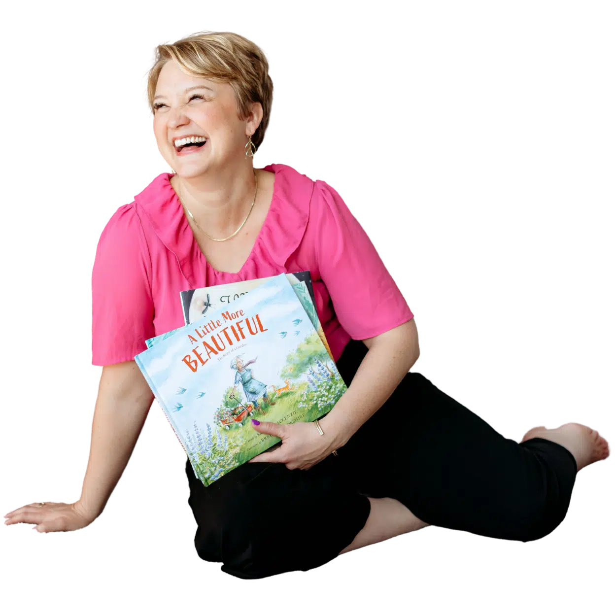 Sarah homepage - Read-Aloud Revival ® with Sarah Mackenzie Smiling woman in a pink blouse sits on the floor, holding a children's book titled A Little More Beautiful.