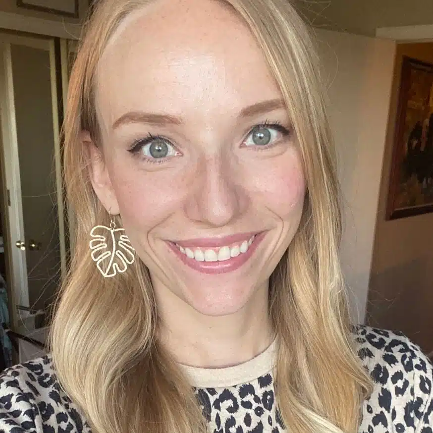 Bridget-Nava - Read-Aloud Revival ® with Sarah Mackenzie Smiling woman with long blonde hair, green eyes, and a large leaf-shaped earring, wearing a leopard-print top indoors in warm light.