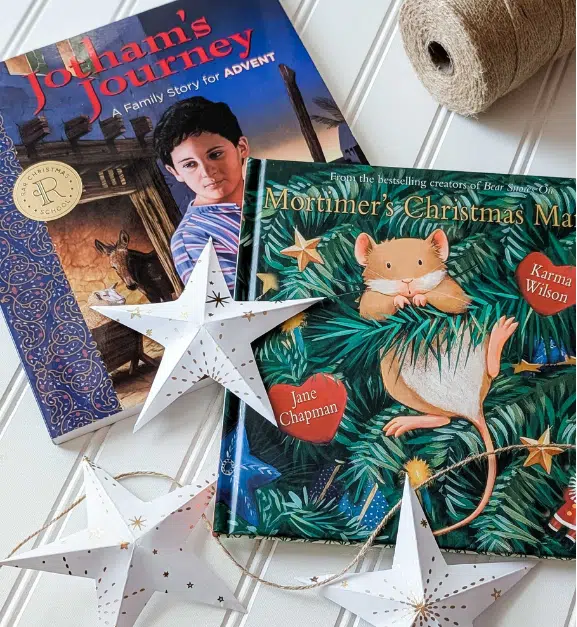 Christmas School Sales 5 - Read-Aloud Revival ® with Sarah Mackenzie Two Christmas-themed children's books, titled Jotham's Journey and Mortimer's Christmas, rest on a white surface with white star decorations and twine nearby.